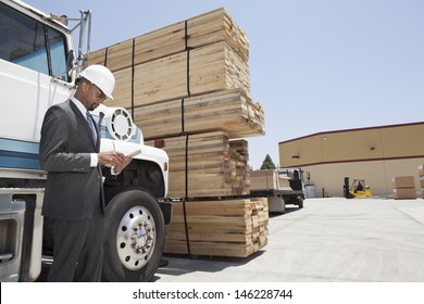 African American Male Contractor Using Tablet PC While Standing By Logging Truck