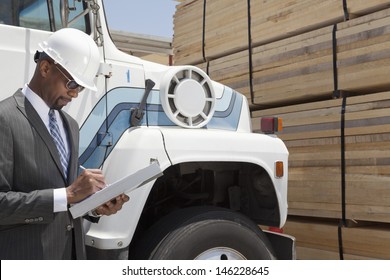 African American Male Contractor Writing Notes While Standing By Logging Truck