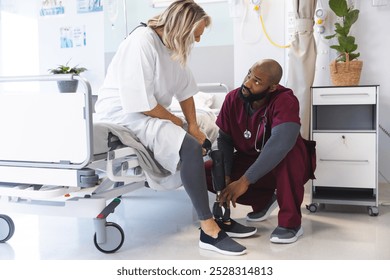 African american male doctor examining senior caucasian female patient with prosthetic leg. Hospital, disability, work, medicine and healthcare, unaltered. - Powered by Shutterstock