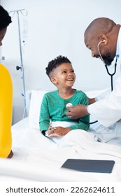 African american male doctor using stethoscope on boy patient in hospital with copy space. Hospital, medical and healthcare services. - Shutterstock ID 2262624611