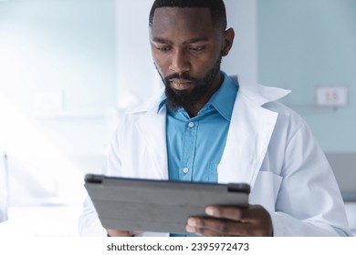 African american male doctor using tablet in hospital room. Medicine, healthcare, communication, work and hospital, unaltered. - Powered by Shutterstock