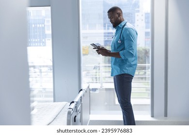 African american male doctor using tablet in hospital room, copy space. Medicine, healthcare, communication, work and hospital, unaltered. - Powered by Shutterstock