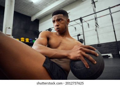 African American male doing an intense workout in the gym. Male athlete doing sit-ups with medicine ball. High quality photo - Powered by Shutterstock