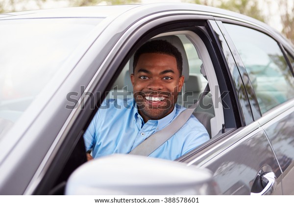 African American male driver looking to camera\
through car window