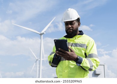 African American male engineer using digital tablet checking system of wind turbine at windmill field farm station. Male engineer monitoring and control windmill system at wind turbines station - Powered by Shutterstock