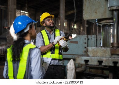 African American male engineer in vest and helmet safety operating control overhead crane for moving heavy metal at factory. Professional technicians in industrial machinery - Powered by Shutterstock