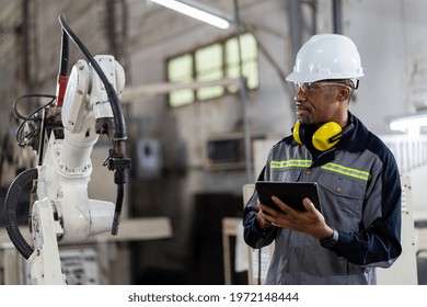 African American male engineer worker using digital tablet control automatic robotic hand machine in factory. Black male technician worker working with control automatic robot arm system welding - Shutterstock ID 1972148444