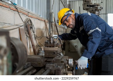 African American male engineer worker maintenance metal machine in the workshop. Black male worker working with lathe machine with safety uniform, goggles and helmet in the industry factory