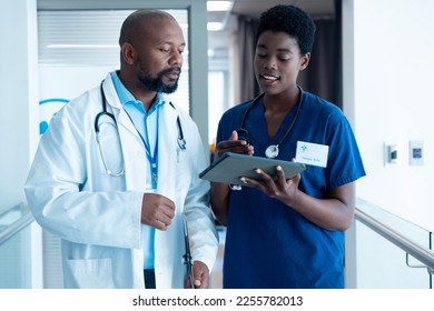 African american male and female doctor using tablet, talking in hospital corridor with copy space. Hospital, medical and healthcare services. - Shutterstock ID 2255782013