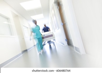 African American Male Female Nursing Staff In Uniform Scrubs With Hospital Bed In Modern Healthcare Centre Motion Blur