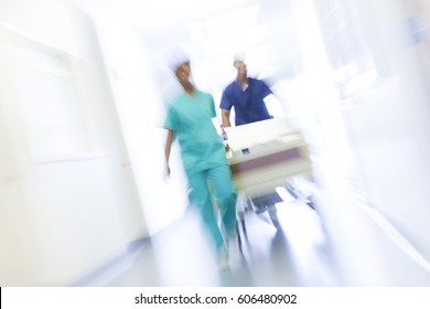 African American Male Female Nursing Staff In Uniform Scrubs With Hospital Bed In Modern Healthcare Centre Motion Blur