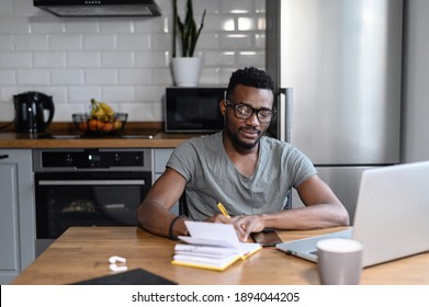 African American Male Freelancer Sitting At The Desk, Look At The Laptop Screen. Happy Young Student Taking Notes, Remotely Studying. Successful Business Man Searching Ideas, Working On Project