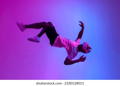 african american male gamer in virtual reality glasses flies in the air and falls in neon lighting, guy plays with vr gadget and levitates, concept of imagination and fantasy - Powered by Shutterstock