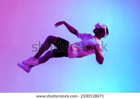 african american male gamer in virtual reality glasses flies in the air and falls in neon lighting, guy plays with vr gadget and levitates, concept of imagination and fantasy