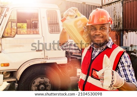 African American male maintenance worker showing thumb up to work outdoors, holding a gallon of oil for maintenance, changing the oil according to the manual that requires transport, moving containers