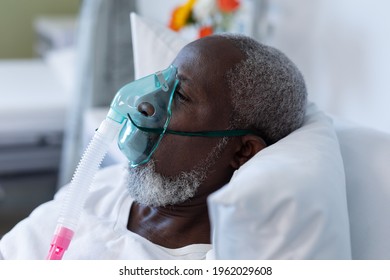 African American Male Patient Lying On Hospital Bed Wearing Oxygen Mask Ventilator. Medicine, Health And Healthcare Services During Coronavirus Covid 19 Pandemic.