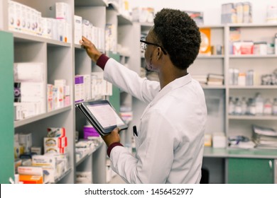 African American male pharmacist using digital tablet during inventory in pharmacy. - Powered by Shutterstock