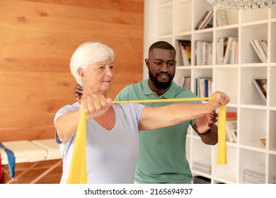 African american male physiotherapist helping senior woman to exercise with resistance bands. Medical care and retirement senior lifestyle concept - Powered by Shutterstock