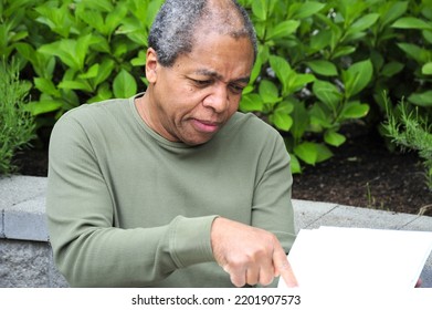 African American Male Reading A Book Outside.