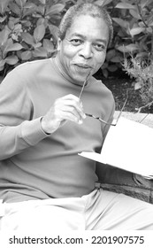 African American Male Reading A Book Outside.