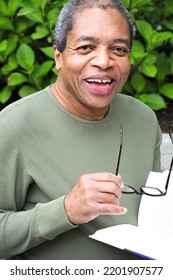 African American Male Reading A Book Outside.