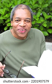 African American Male Reading A Book Outside.