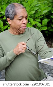 African American Male Reading A Book Outside.