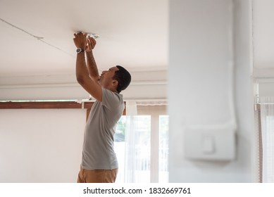 African American Male Replacing LED Lamp At Home. Black Man Changing Light Bulb During COVID-19 Quarantine, Brazilian With Housework And Maintenance While Virus Pandemic, Power Saving Concept. 