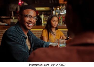 African american male smiling while enjoying time with friends in restaurant  - Powered by Shutterstock