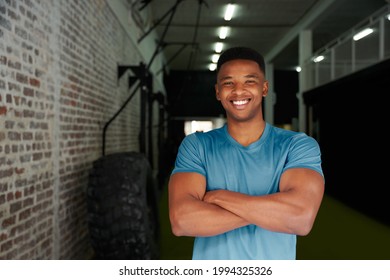 African American Male Standing With Crossed Arms In The Gym. Male Personal Trainer Looking Intensely At The Camera. High Quality Photo