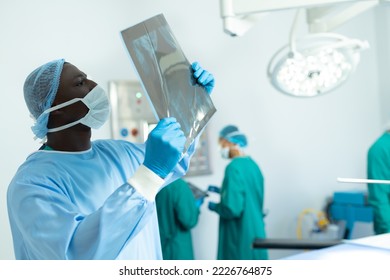 African american male surgeon studying x-ray in operating theatre, with copy space. Hospital, medical and healthcare services. - Powered by Shutterstock