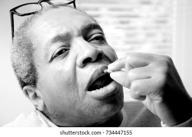 African American Male Taking Blood Pressure Medication At Home.