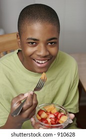 African American Male Teen Eating Fruit In Bowl