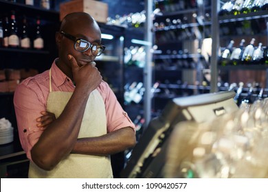 African American Male Waiter Standing At Bar Counter And Looking At Computer Screen With POS System Thoughtfully