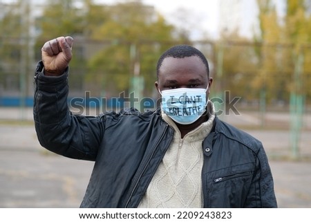 African american man activist in medical mask with an inscription I CAN'T BREATHE at single picket. Black Lives Matter, BLM, racial discrimination, mass protests in USA