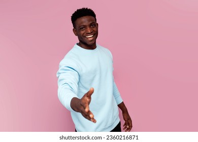 african american man in blue sweater gives his hand on pink isolated background, man makes handshake and says welcome - Powered by Shutterstock