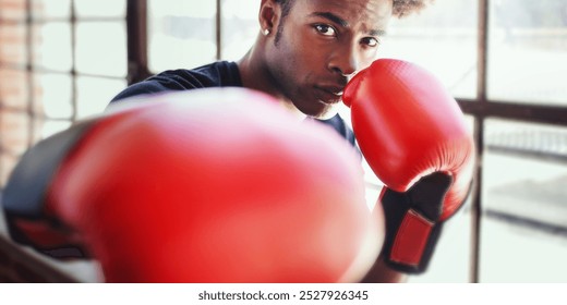 African American man boxer training with red boxing gloves. Boxer focus on training, African American man athlete in boxing stance, punching with boxing gloves. African American man boxer training - Powered by Shutterstock