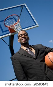 African American Man In A Business Suit Posing With A Basketball.  He Could Be A Coach Player Recruiter Or Trainer.