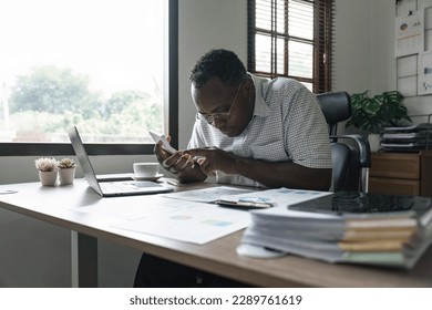 African American man calculating using machine managing household finances at home, focused biracial male make calculations on calculator account taxes or expenses - Powered by Shutterstock