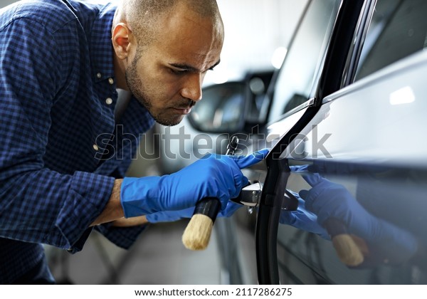 African American man car service worker applying nano\
coating on a car