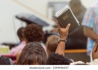 African American Man at Church with a Bible Raised