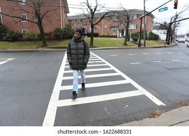 An African American Man Crossing The Road. A Black Man Walking On The Zebra Crossing. Road Safety. Winter And Cold