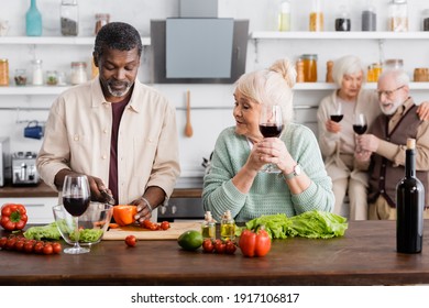 African american man cutting bell pepper near senior woman and retired friends on blurred background - Powered by Shutterstock