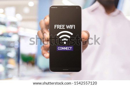 African american man demonstrating smartphone connected to free wifi hotspot in shopping center, selective focus on device