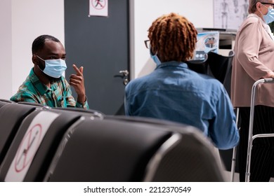 African American Man Discussing Treatments With Laughing Hair Woman In Hospital Waiting Room. Culturally Close Patients Chatting At Family Area Of Infirmary. Sick People Talking Each Other In Medical