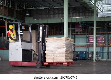 African American Man Driver Warehouse Worker In Safety Vest And Helmet On Forklift Truck In Industry Factory.