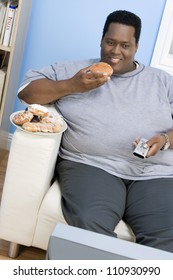 African American Man Eating Donut While Watching Television African American Man Eating Donut While Watching Television