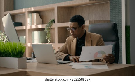 African American man entrepreneur office manager guy male businessman working at desk with laptop read documents check graphics charts business paperwork analyzing data upset financial problem mistake - Powered by Shutterstock