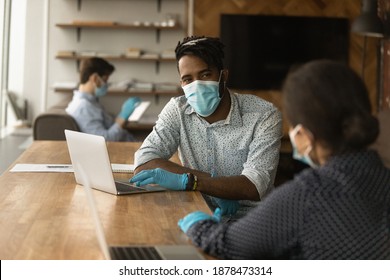 African American man in facial mask and rubber gloves from coronavirus talk with female colleague in office. Diverse employees in facemasks work together at coworking workplace. Covid-19 concept. - Powered by Shutterstock