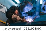 African American man is focused on work. Uniformed welder lifts protective mask and look straight at camera. Male is happy and smiles. Men